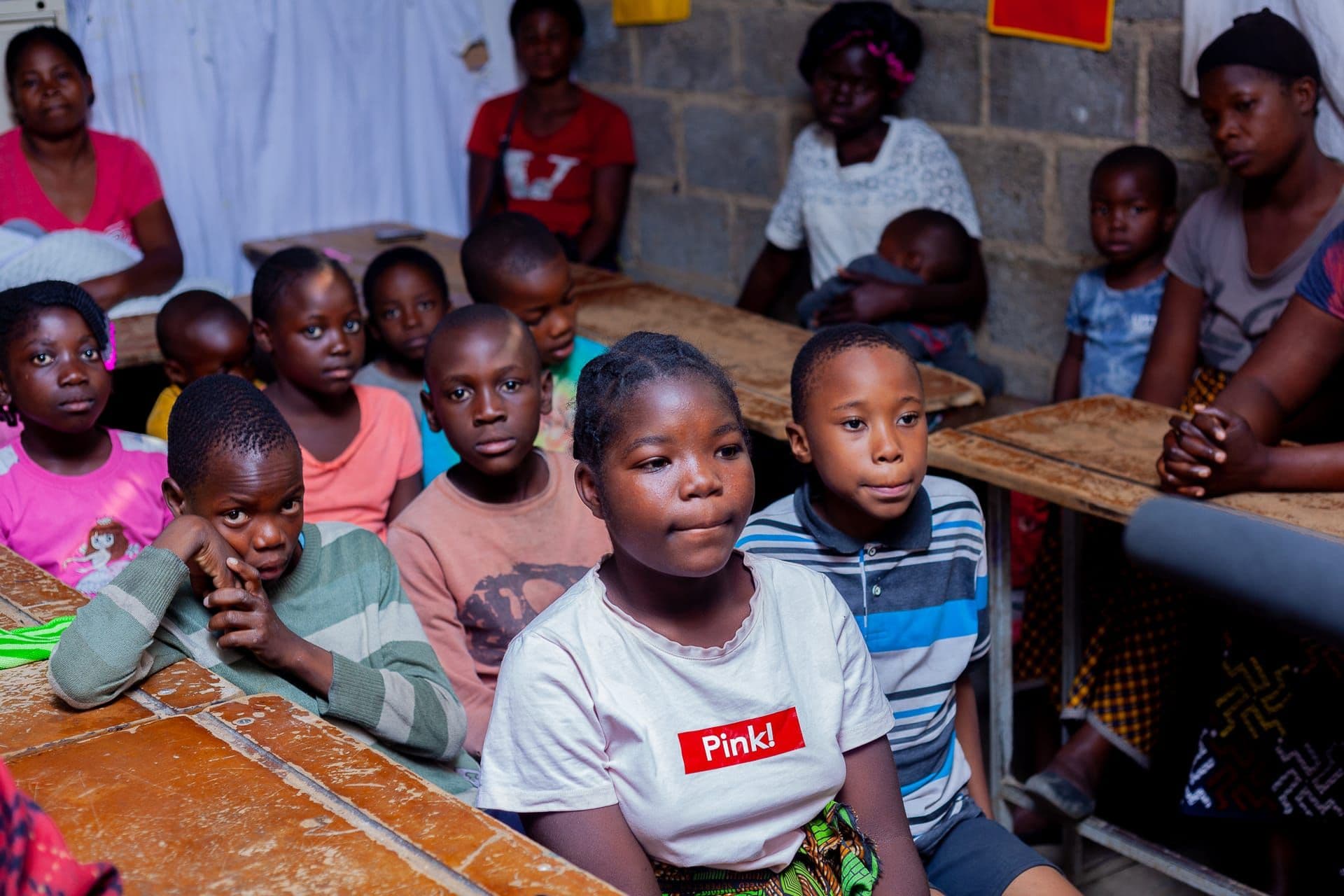 Children in a classroom raising their hands during a lesson